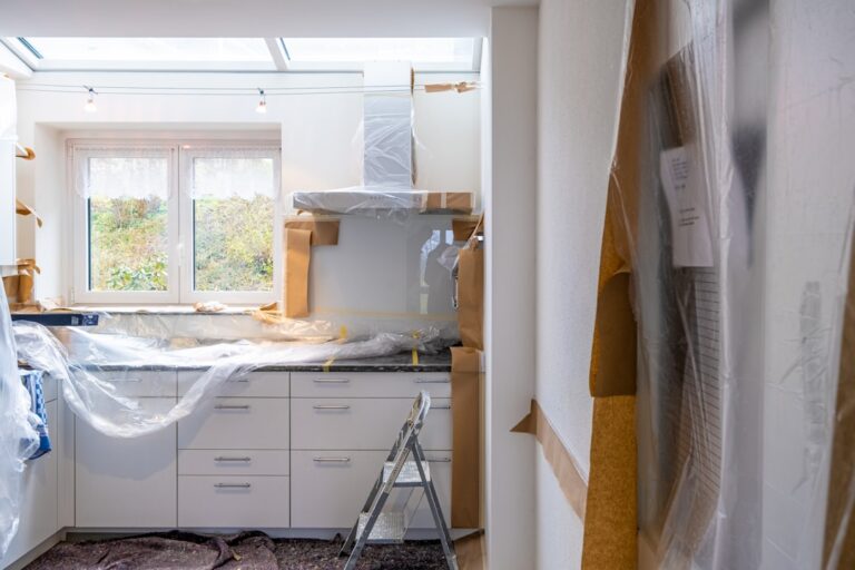 A contractor and homeowner reviewing renovation plans and documents at a residential construction site.